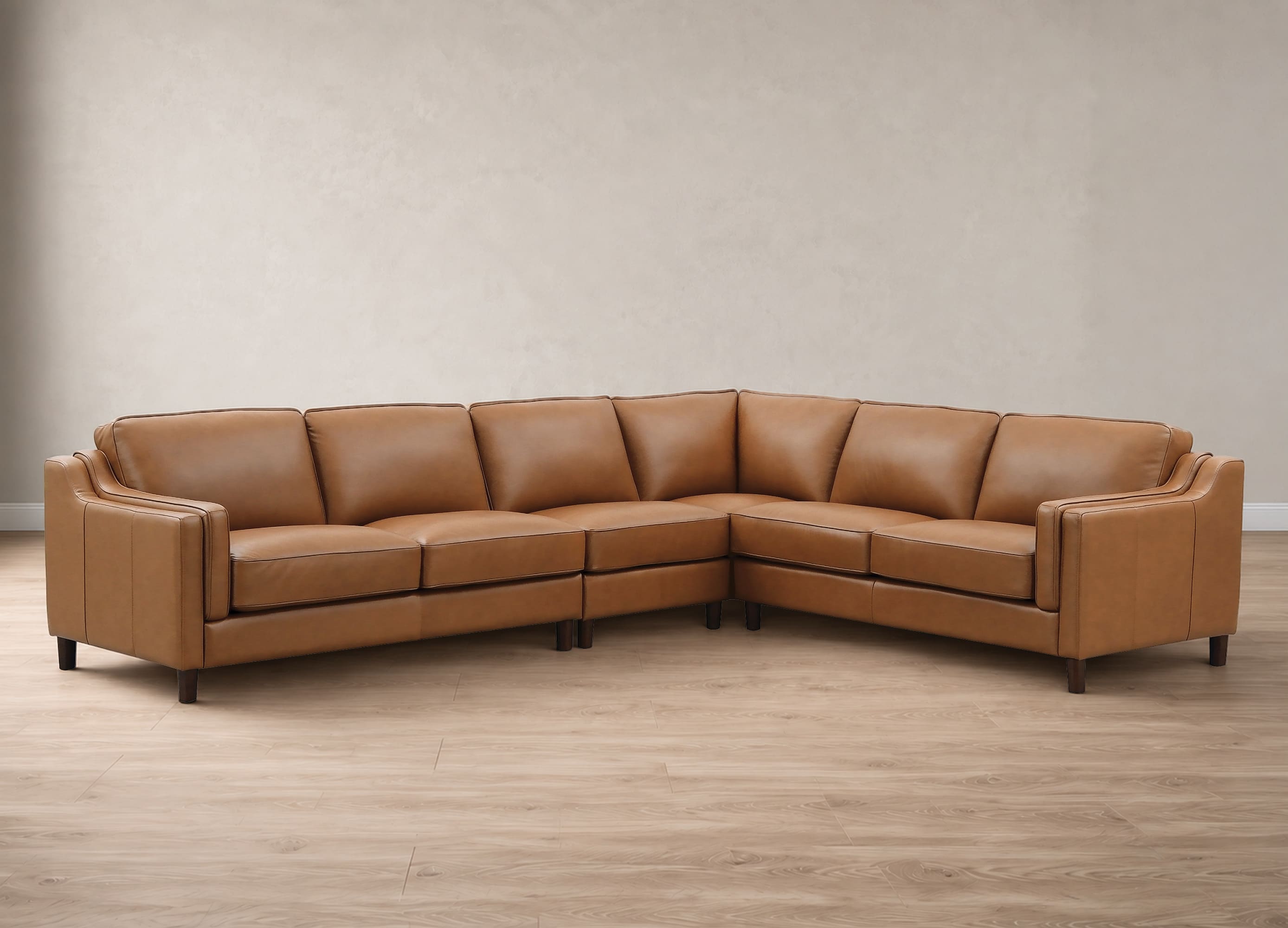 A curved sectional sofa upholstered in tan leather, shown in a staged room with a textured beige wall and light wood floor.