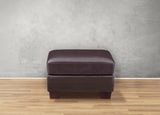 Brown leather ottoman on a wooden floor with a gray wall background