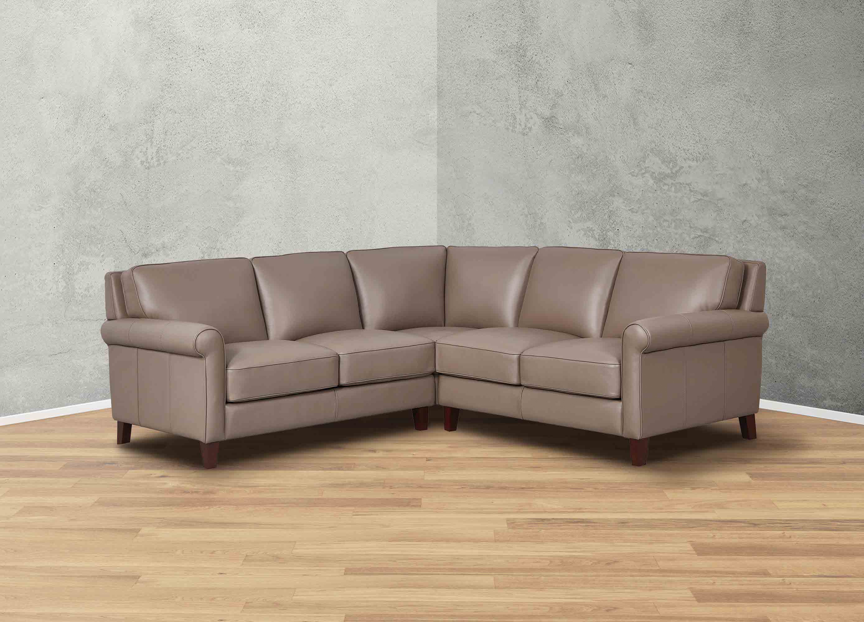 Brown leather sectional sofa in a room with a gray wall and wooden floor.