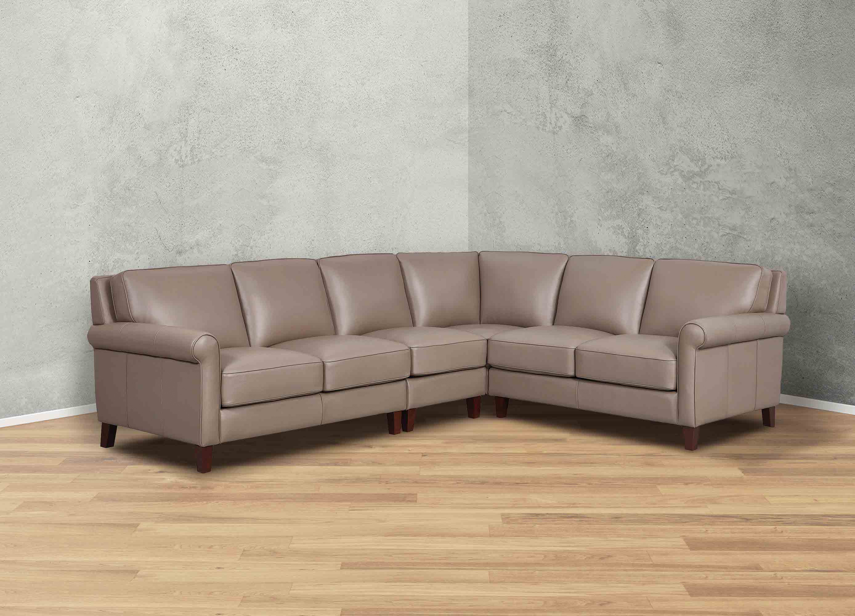 Brown leather sectional sofa in a room with gray walls and wooden flooring.