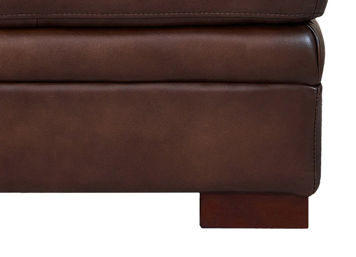 Close-up of a brown leather sofa corner on a white background