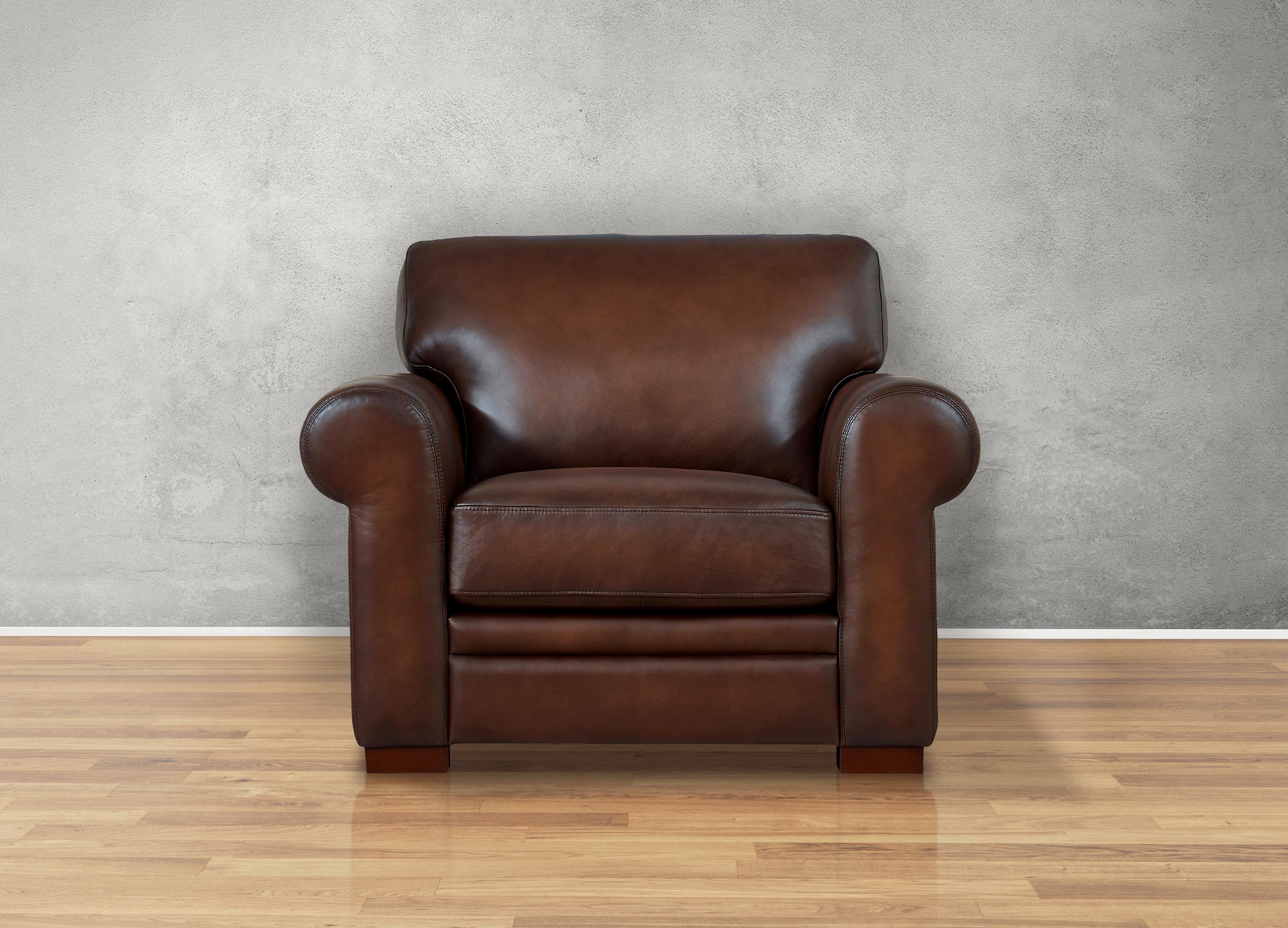 Brown leather armchair on a wooden floor with a gray wall background