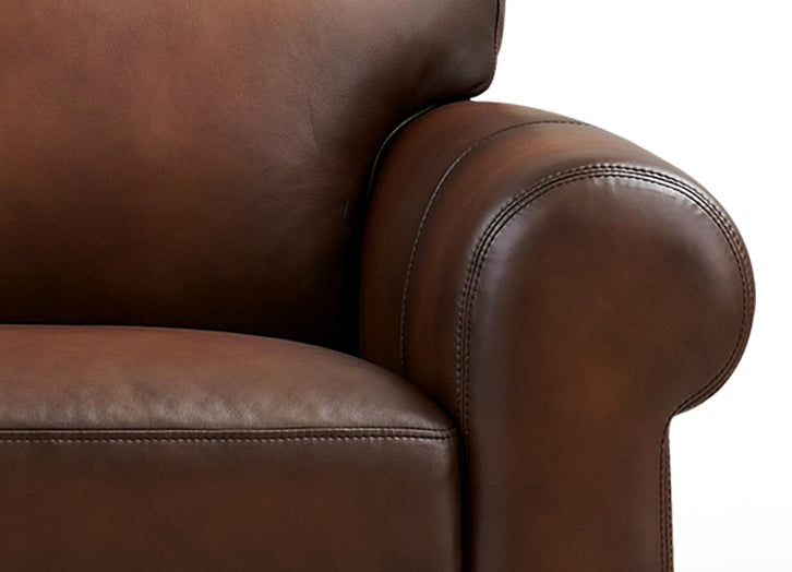 Close-up of a brown leather armchair with visible stitching