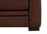 Close-up of a brown leather sofa corner on a white background
