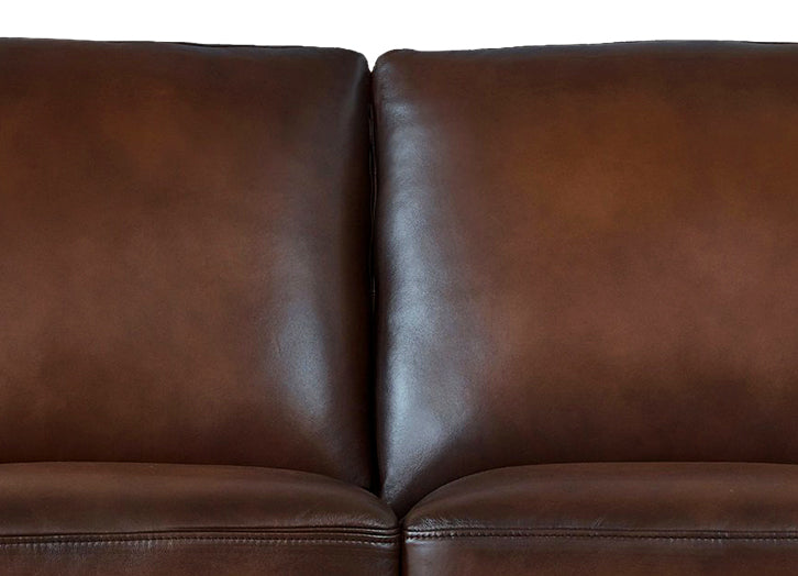 Close-up of a brown leather sofa with a plain background