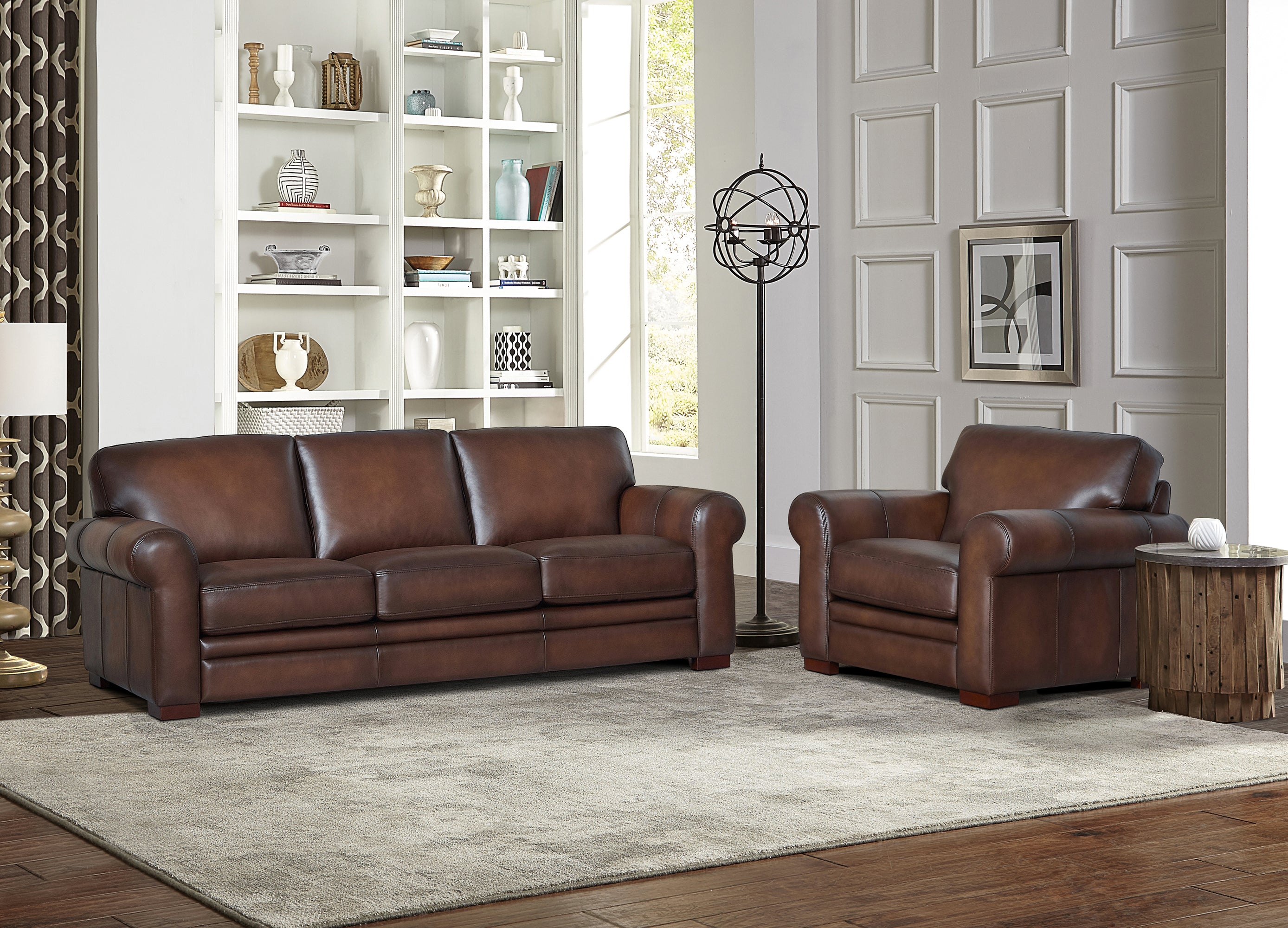 Brown leather sofa and armchair in a living room setting with decorative items on shelves.