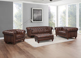 Brown leather sofa set in a living room with large windows.