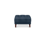 A navy blue tufted ottoman with dark brown wooden legs, shown from the front on a solid white background.
