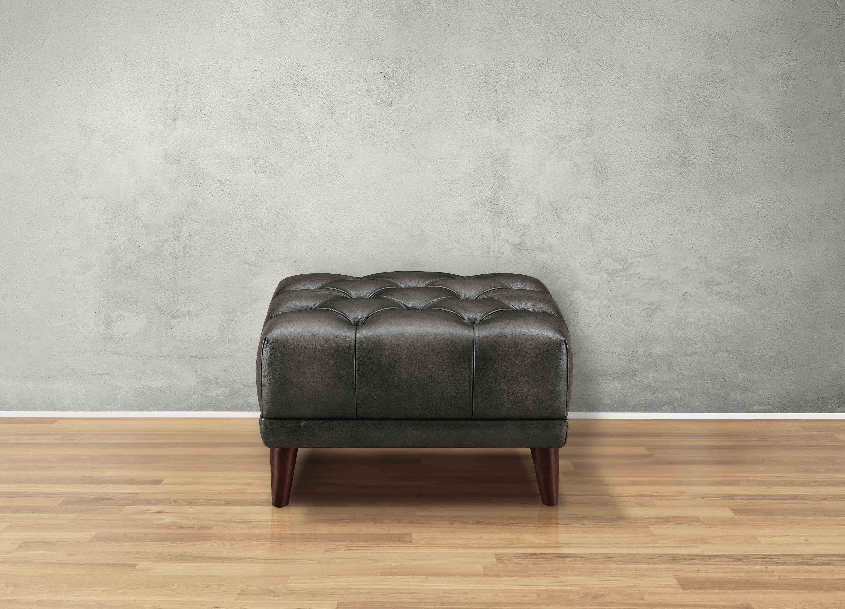 Brown leather ottoman on a wooden floor with a gray wall background