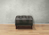 Brown leather ottoman on a wooden floor with a gray wall background