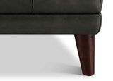 Close-up of a brown leather sofa with wooden legs on a white background