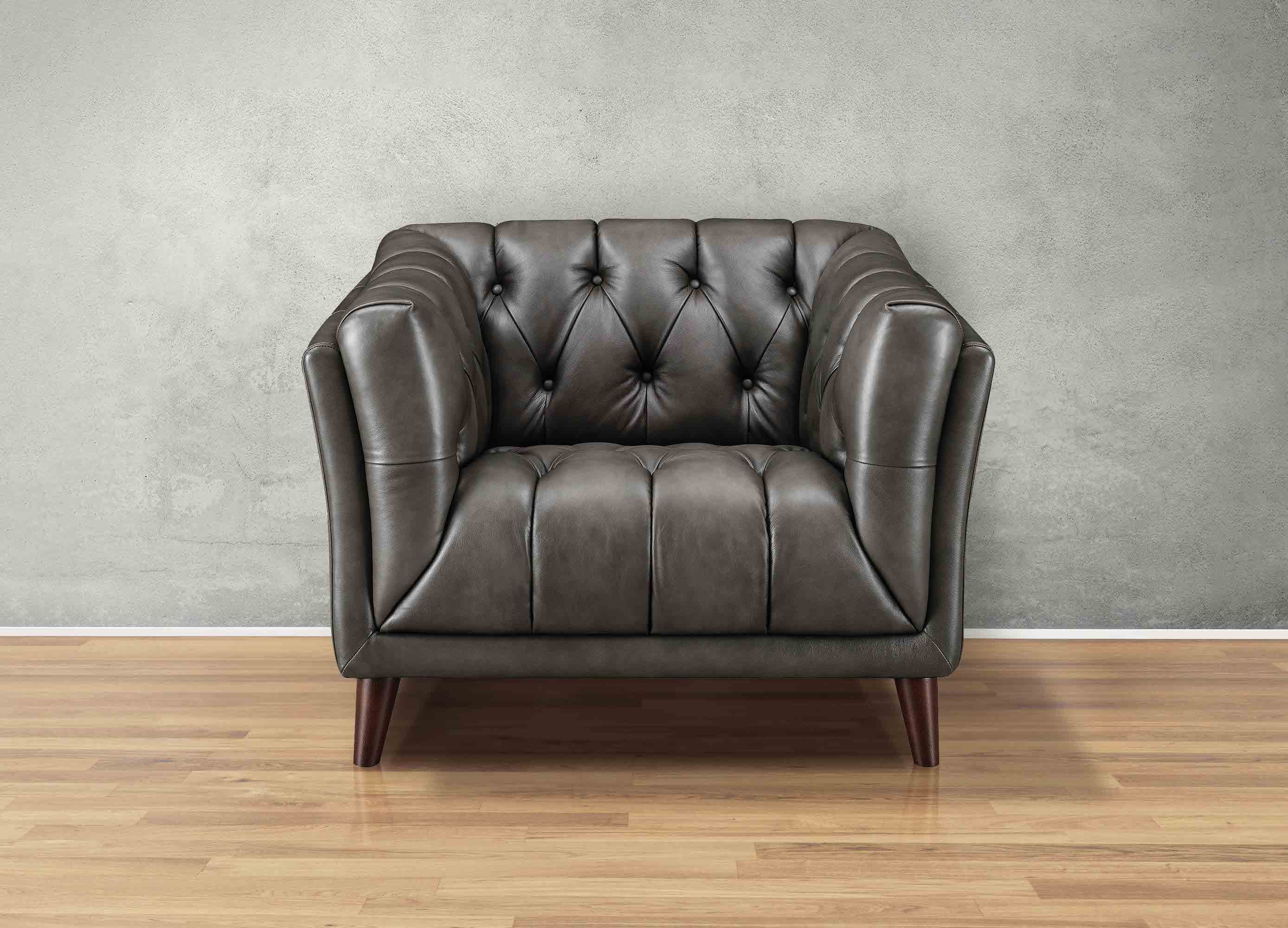 Brown leather armchair against a gray wall on a wooden floor