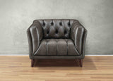 Brown leather armchair against a gray wall on a wooden floor