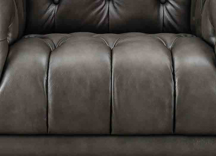 Close-up of a brown leather sofa with tufted backrest