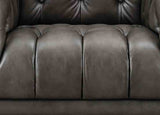 Close-up of a brown leather sofa with tufted backrest