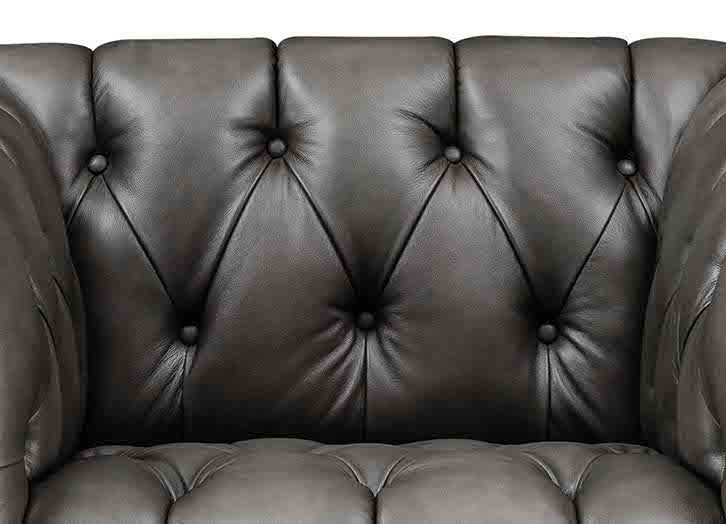 Close-up of a brown leather sofa with tufted backrest