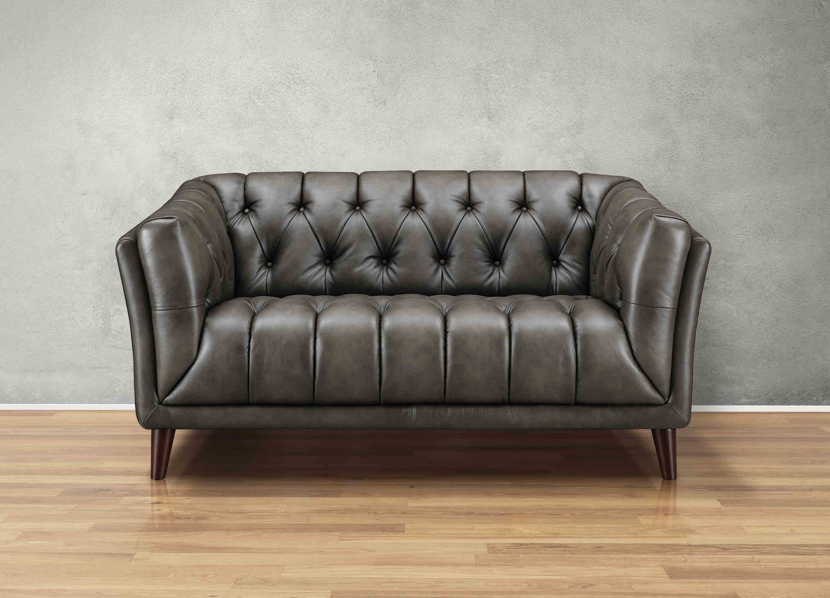 Brown leather sofa on a wooden floor with a gray wall background