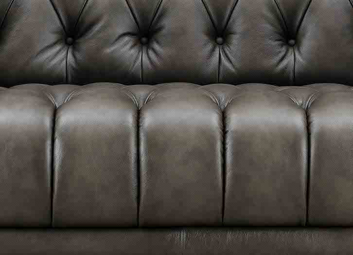 Close-up of a brown leather sofa with tufted backrest