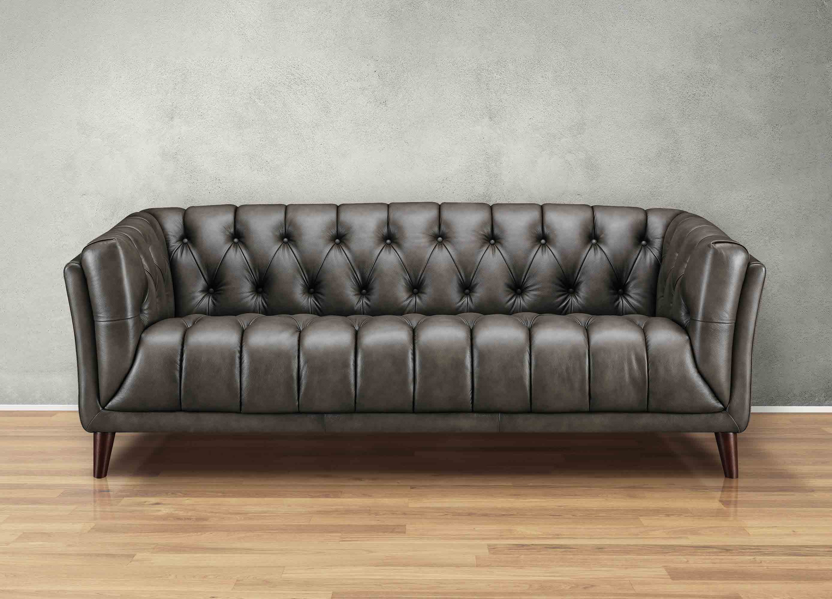 Brown leather sofa against a gray wall on a wooden floor