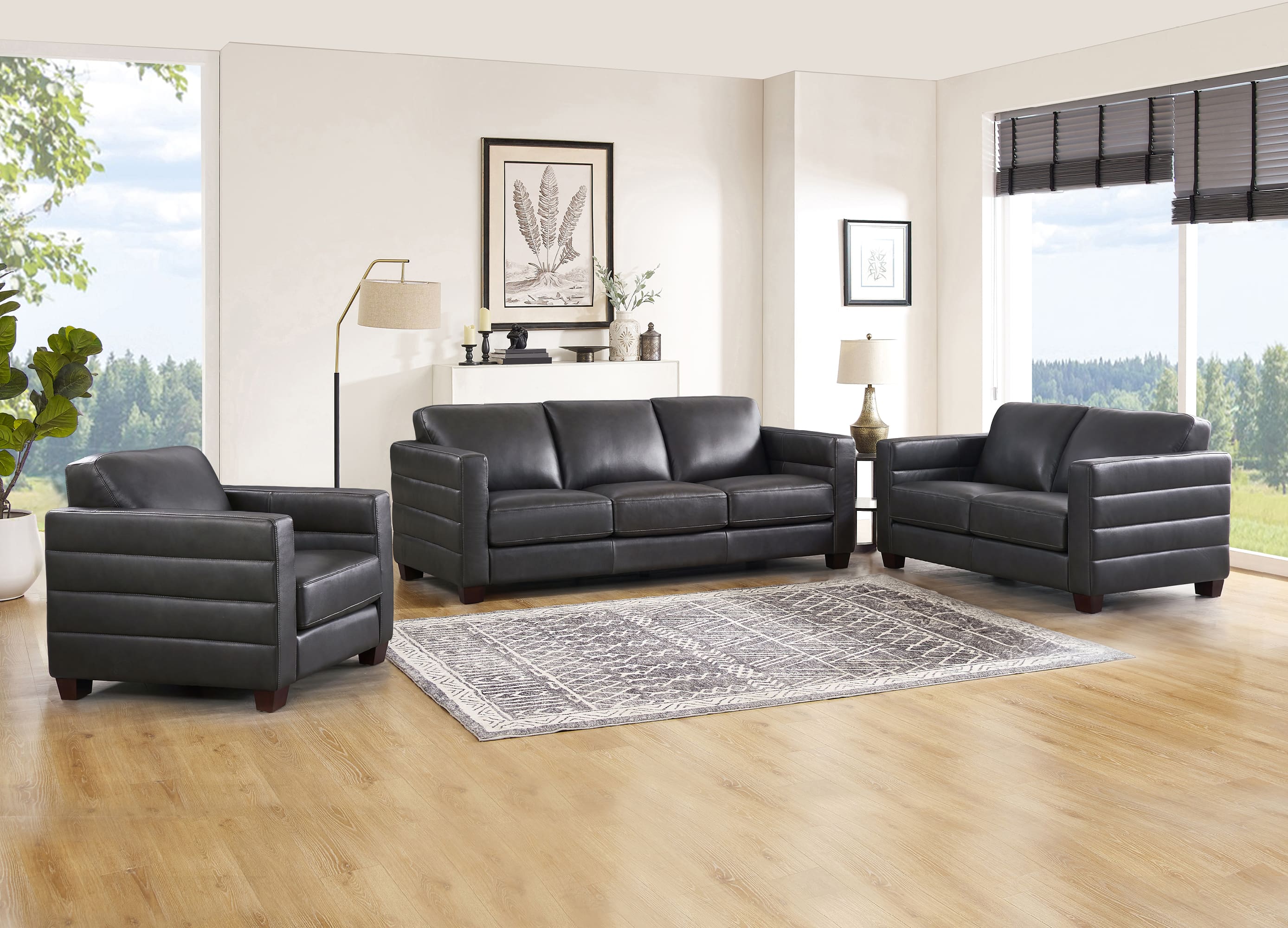 Black leather sofa set in a living room with large windows and decor.