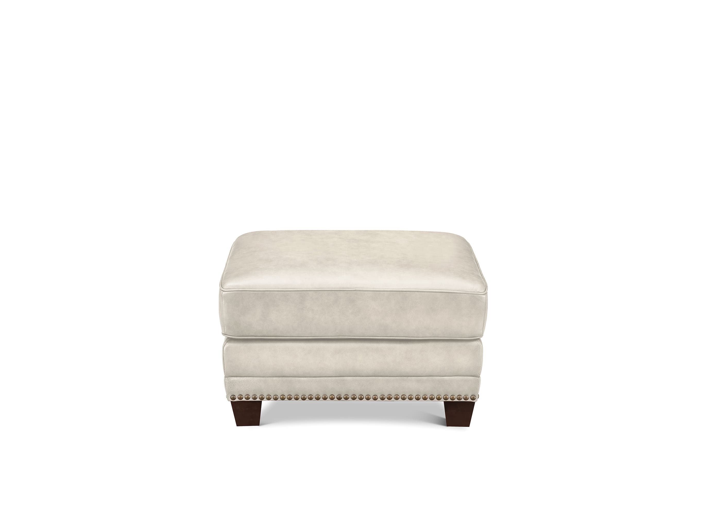A square upholstered ottoman in a light cream or off-white fabric, featuring dark brown wooden legs and nailhead trim along the front edge, shown against a plain white background.