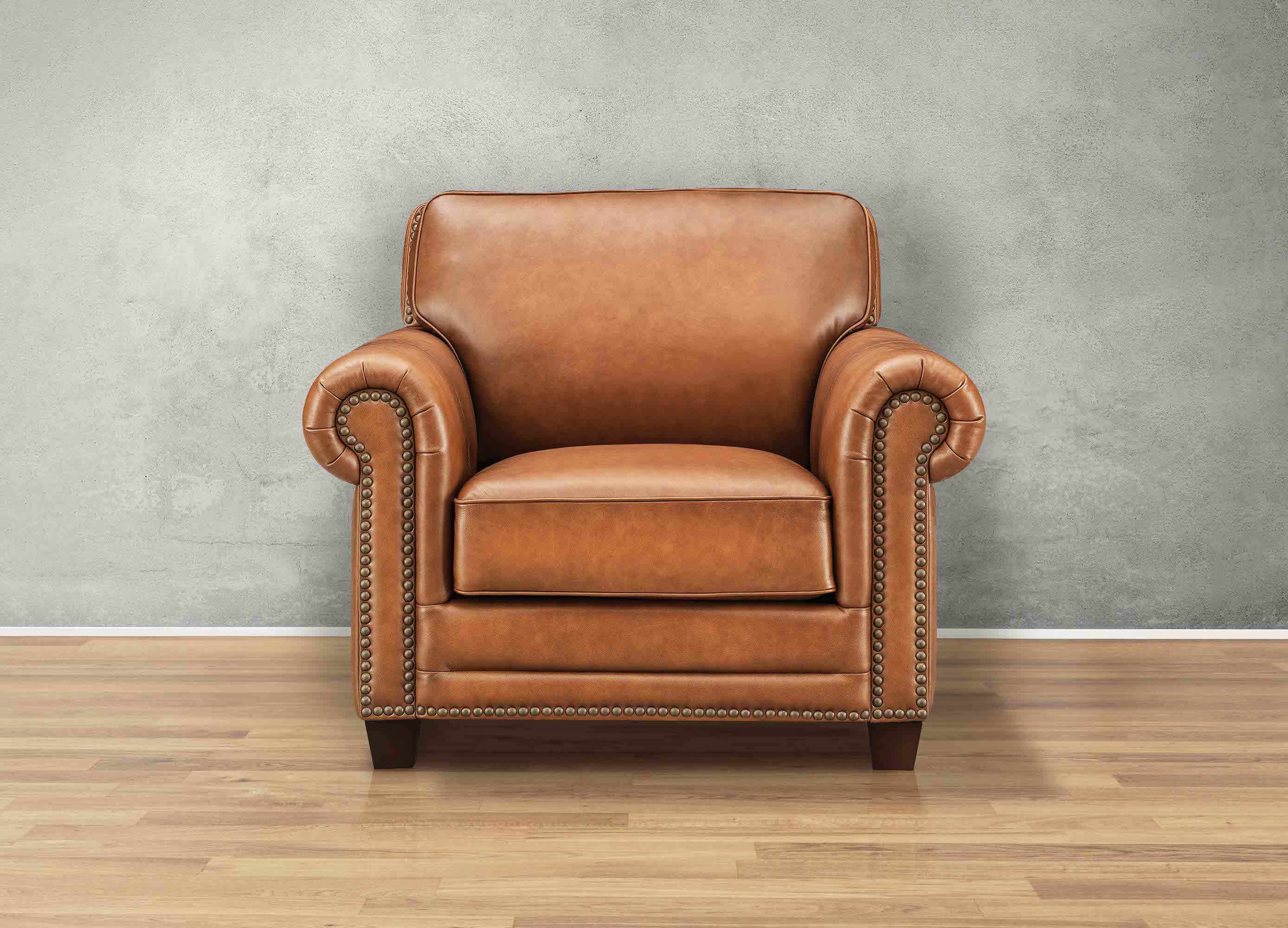 Brown leather armchair against a gray wall on a wooden floor