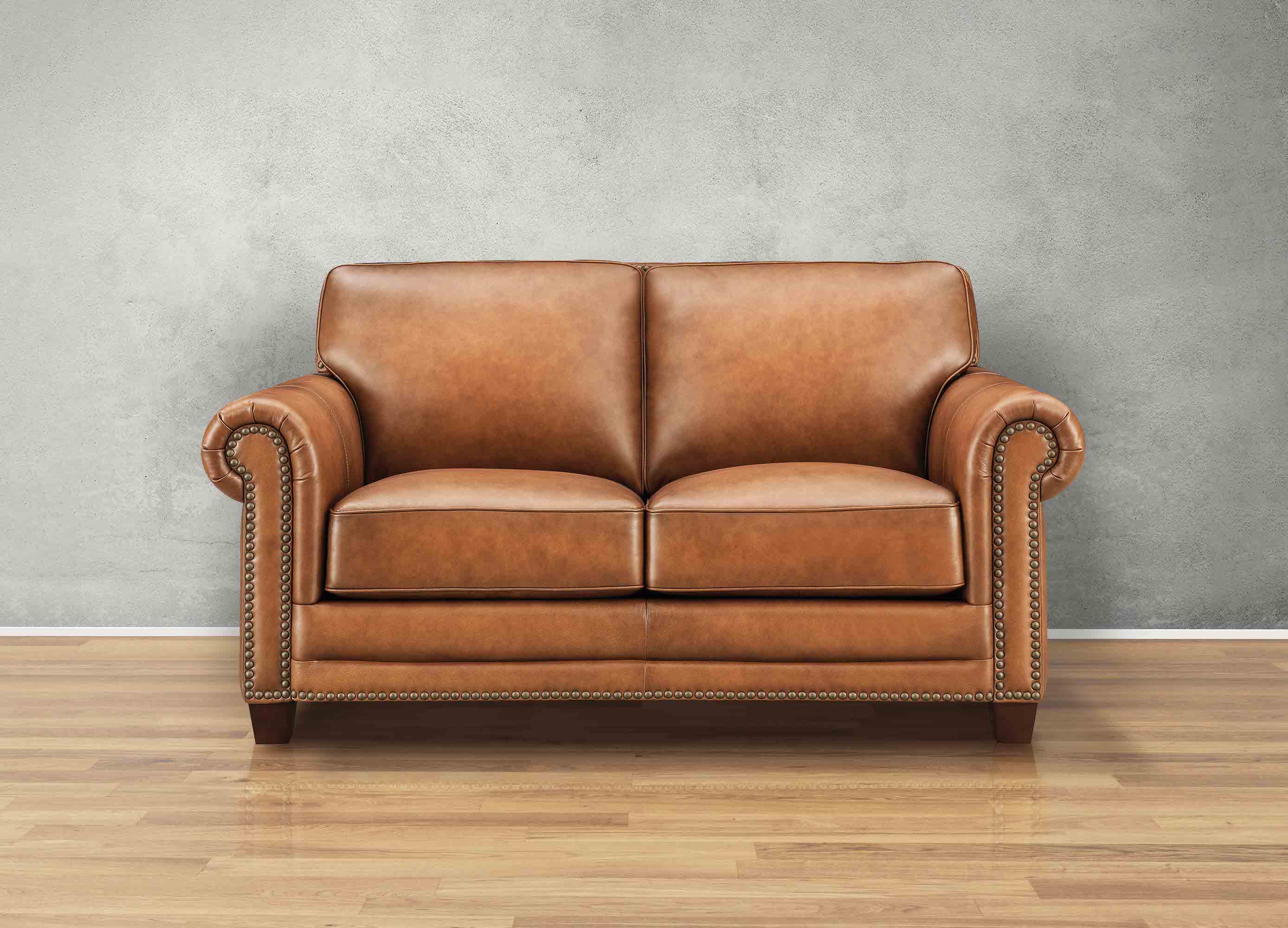 Brown leather sofa on a wooden floor with a gray wall background