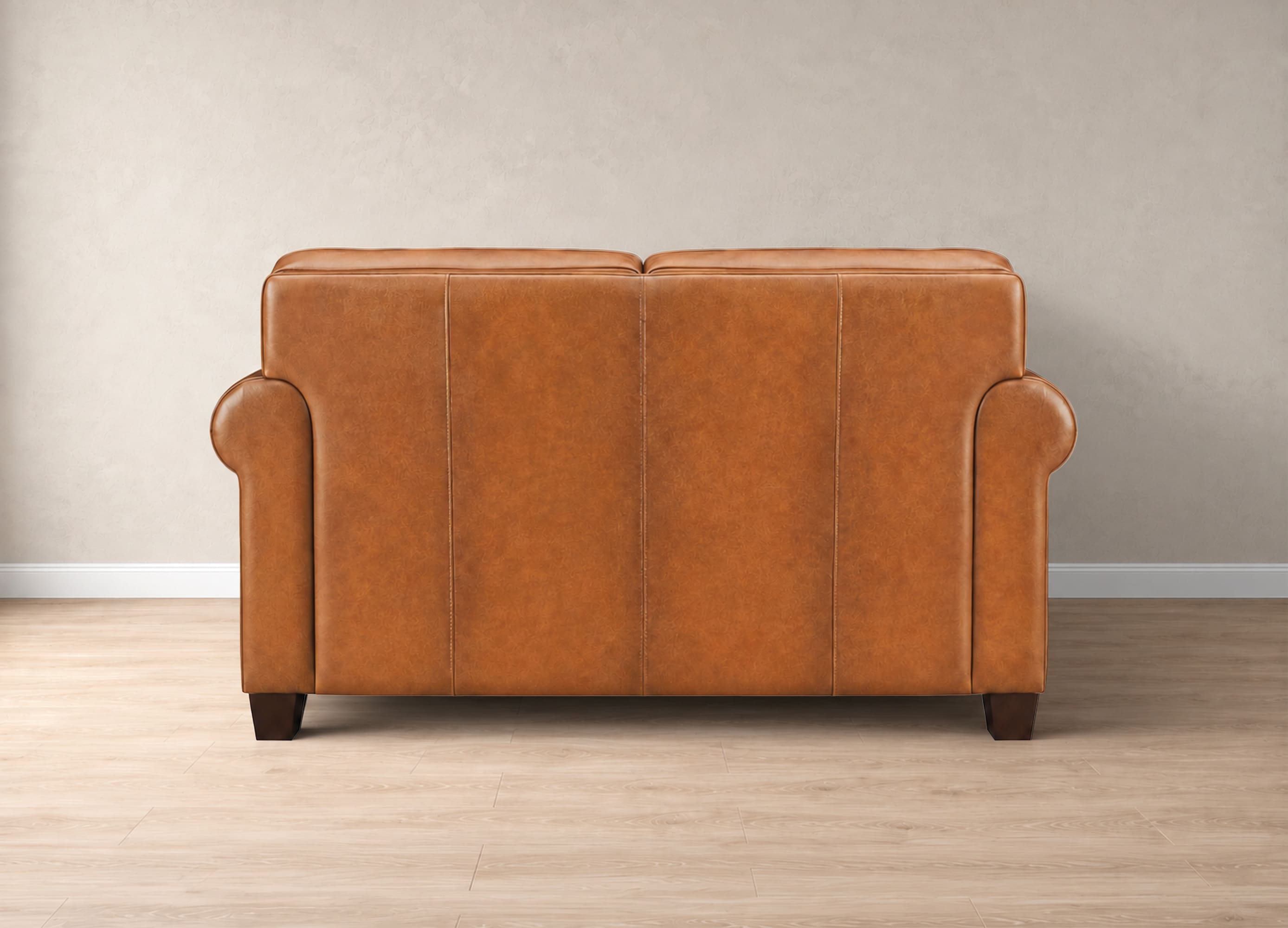 A classic two-seater sofa upholstered in warm cognac brown leather, shown from the back against a neutral beige wall and light wood floor.