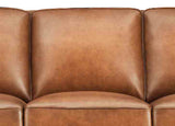 Close-up of a brown leather sofa with a plain background