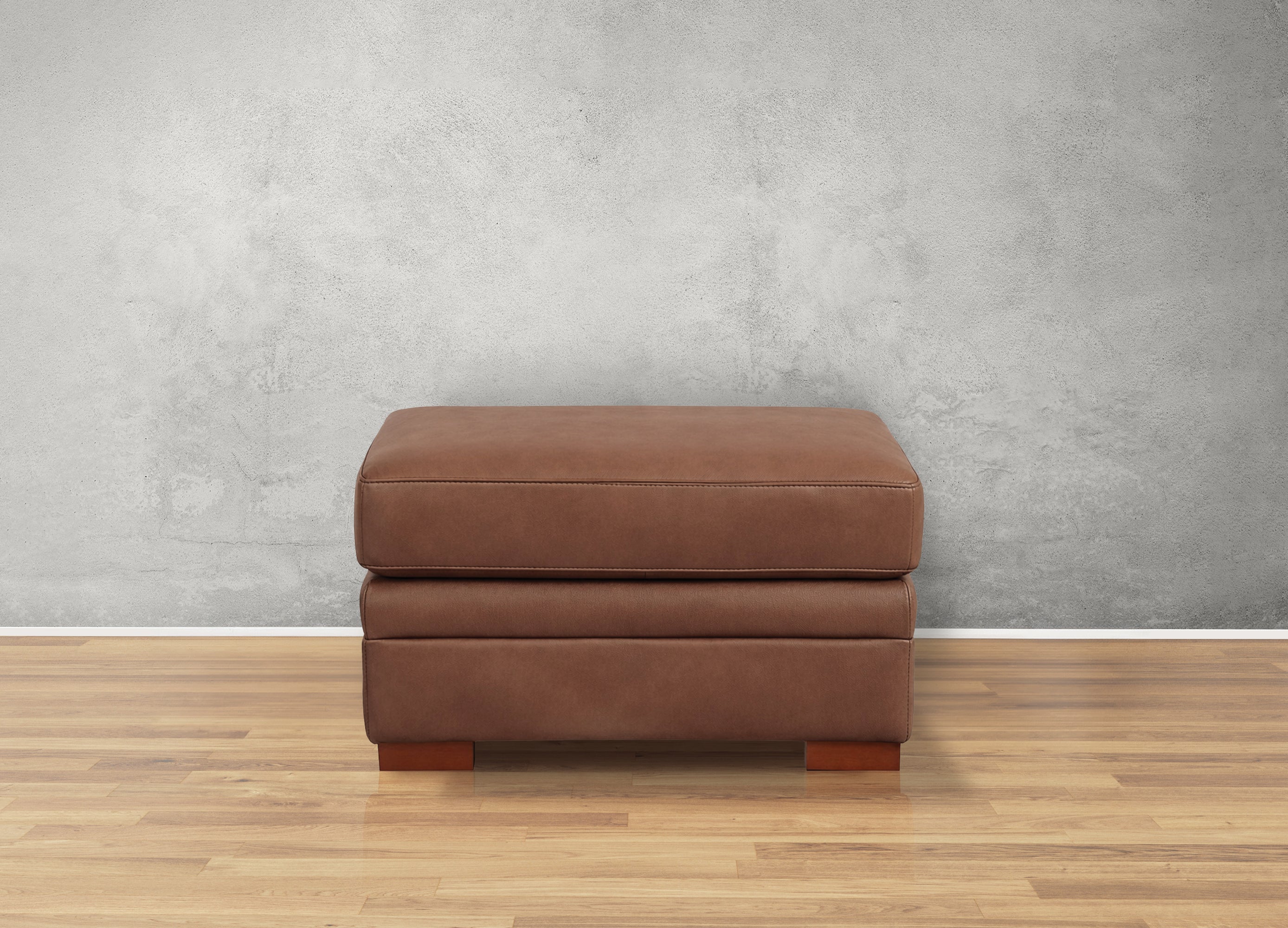 Brown ottoman on a wooden floor with a gray wall background