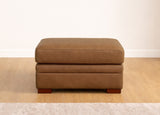 Brown ottoman on a wooden floor with a white wall background
