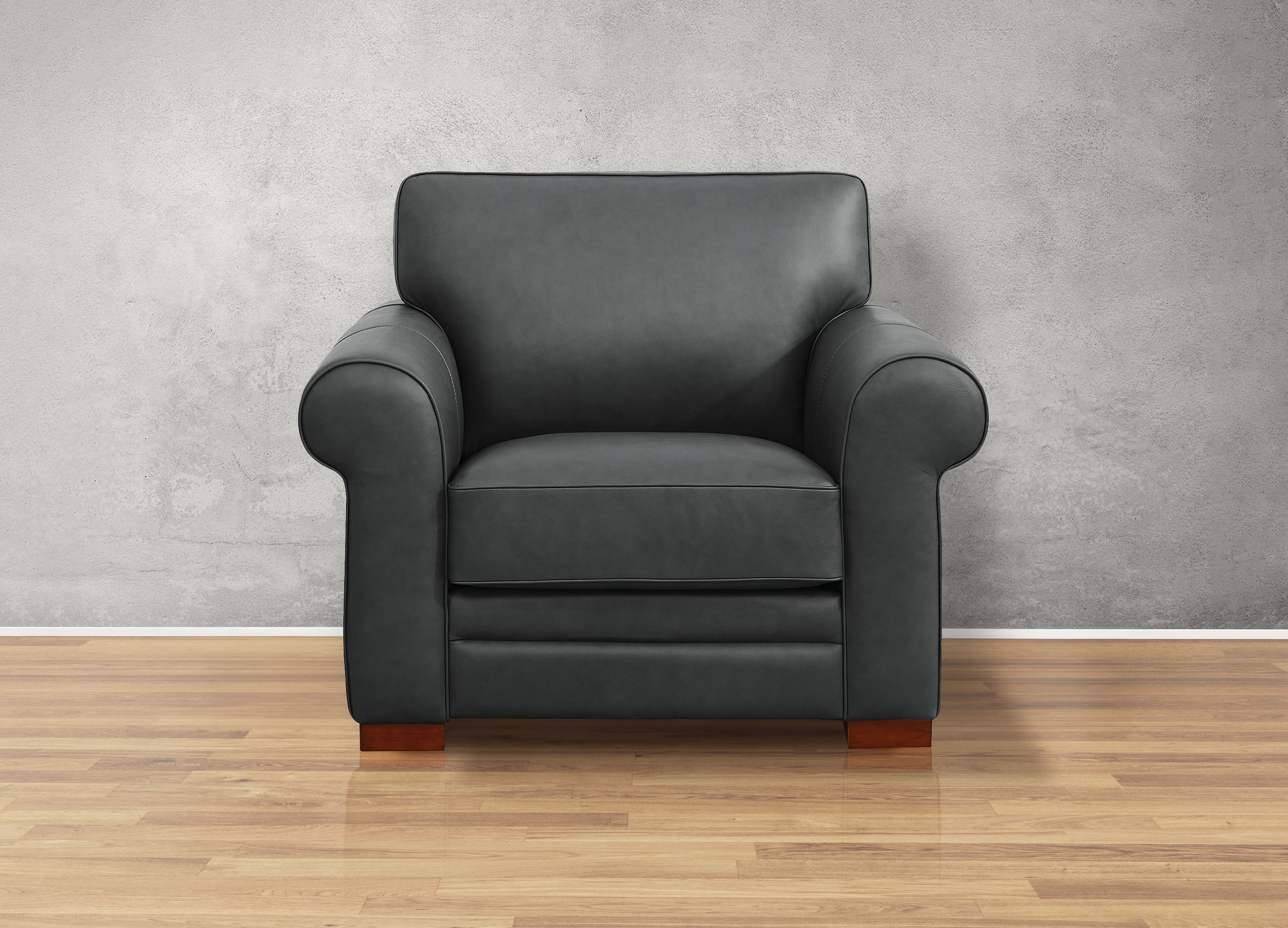 Black leather armchair on a wooden floor with a gray wall background