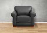 Black leather armchair on a wooden floor with a gray wall background