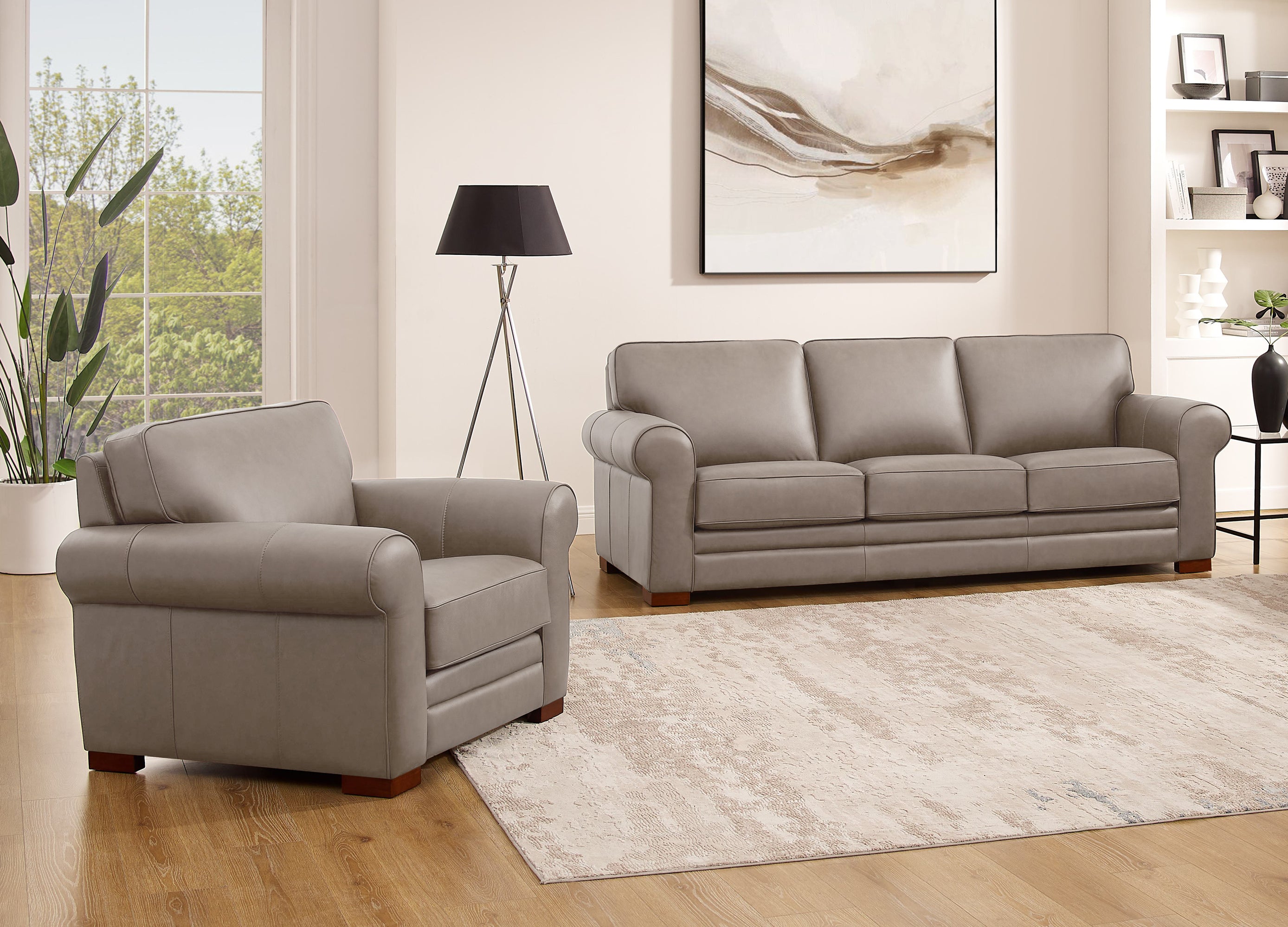Gray sofa and armchair set in a living room with a rug and lamp.