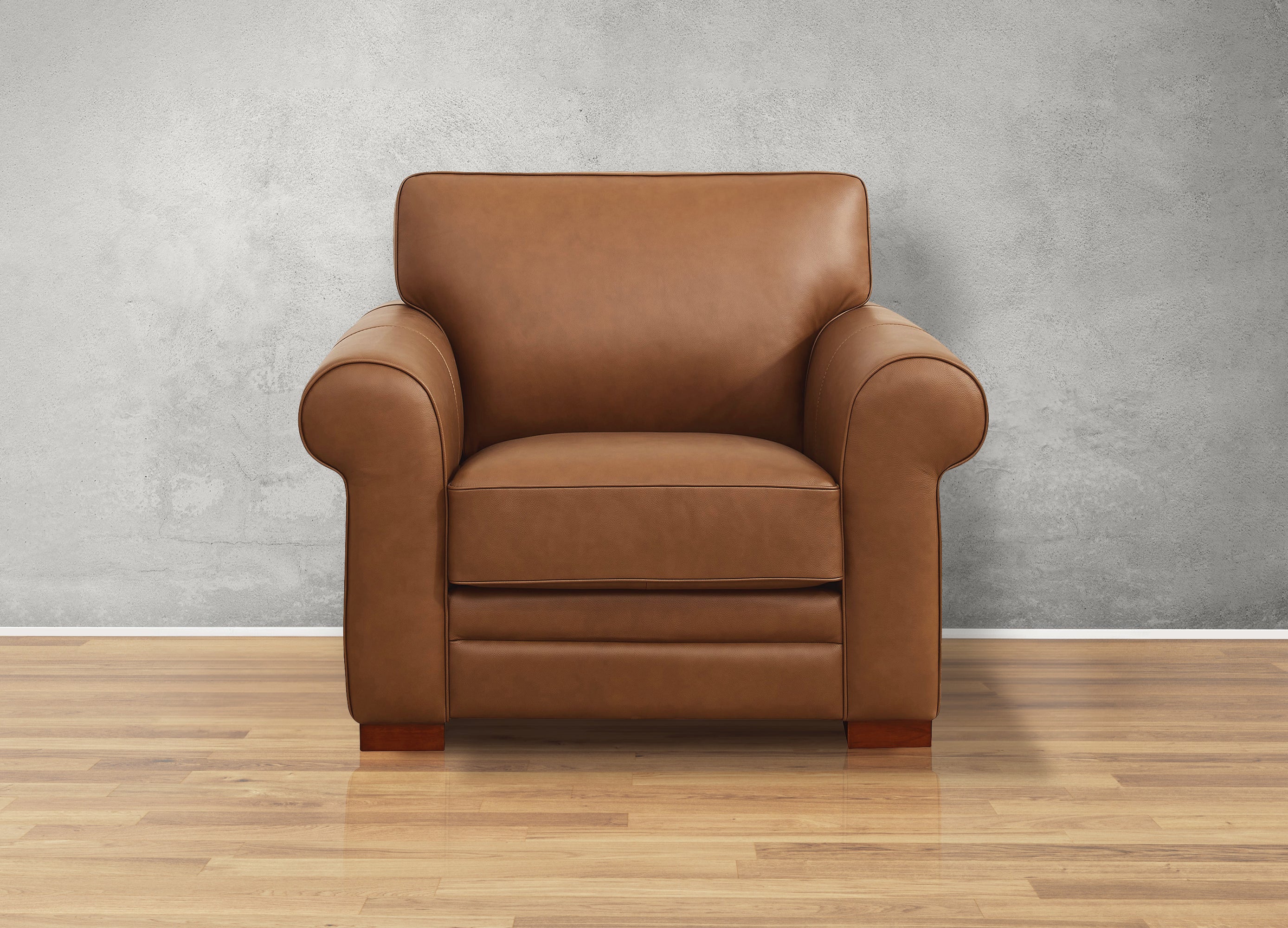 Brown leather armchair on a wooden floor with a gray wall background