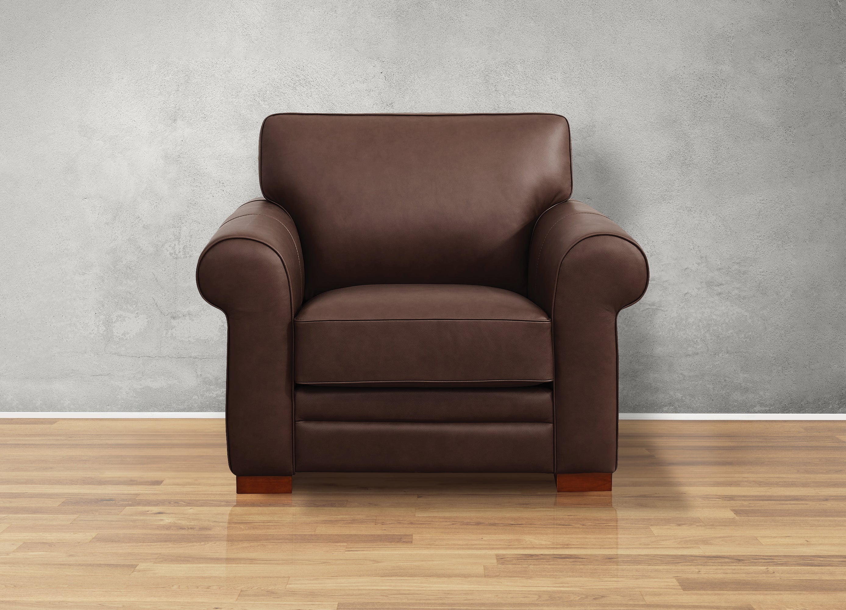 Brown leather armchair on a wooden floor with a gray wall background