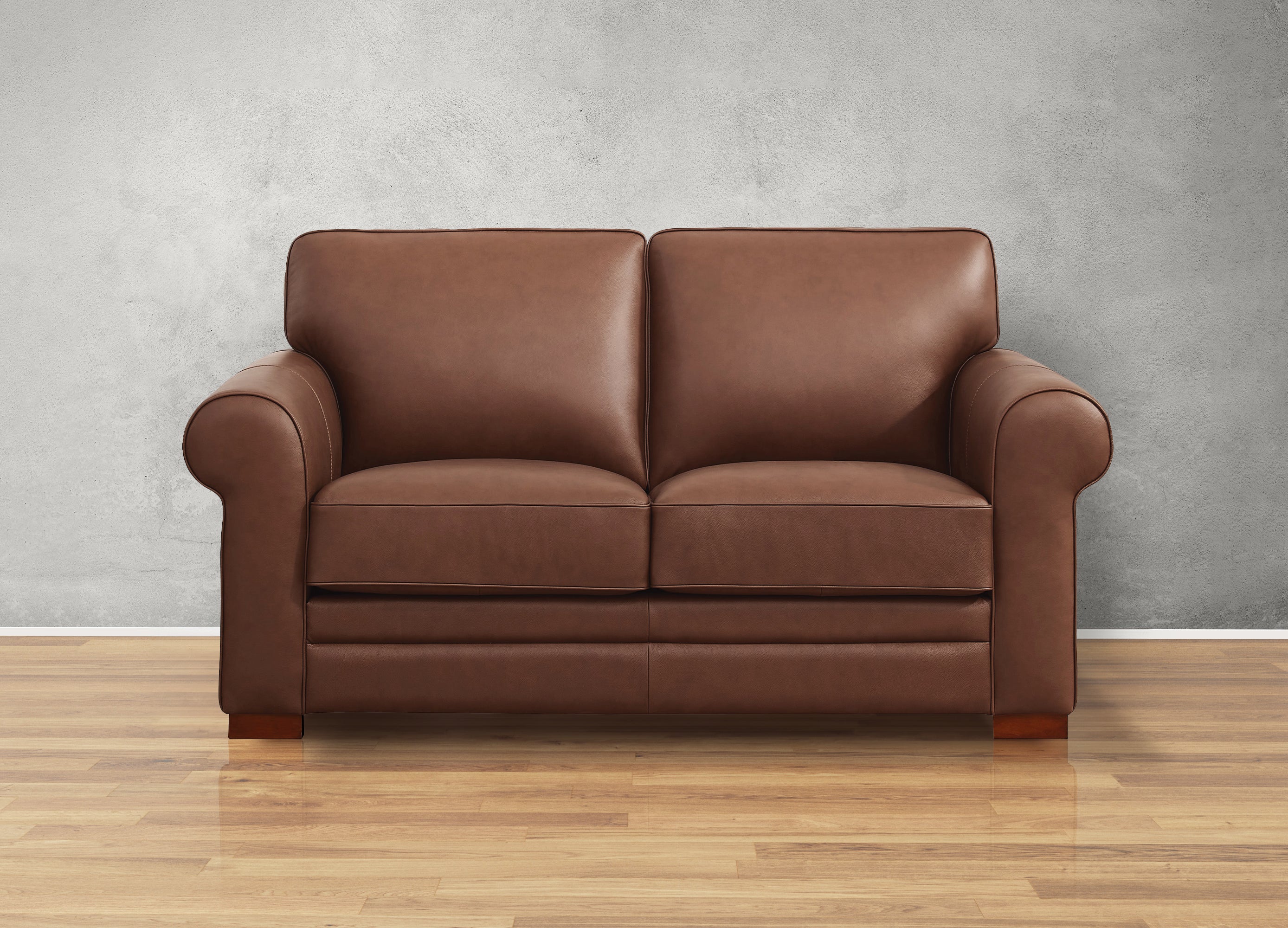 Brown leather sofa on a wooden floor with a gray wall background