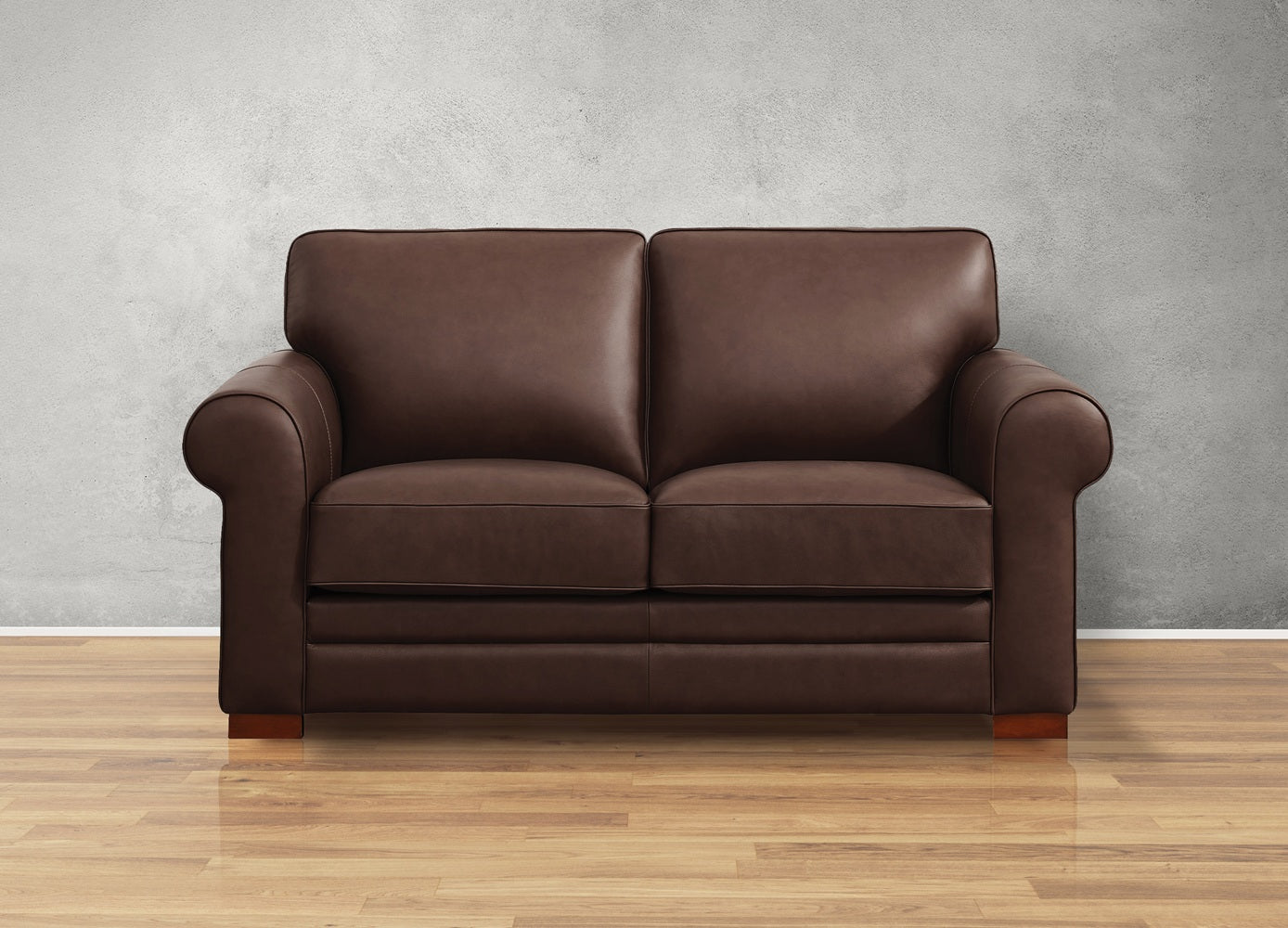 Brown leather sofa on a wooden floor with a gray wall background