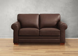 Brown leather sofa on a wooden floor with a gray wall background