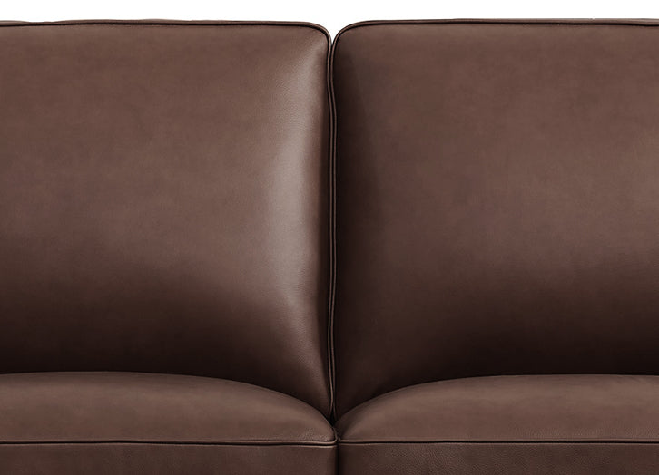 Close-up of a brown leather sofa with a white background
