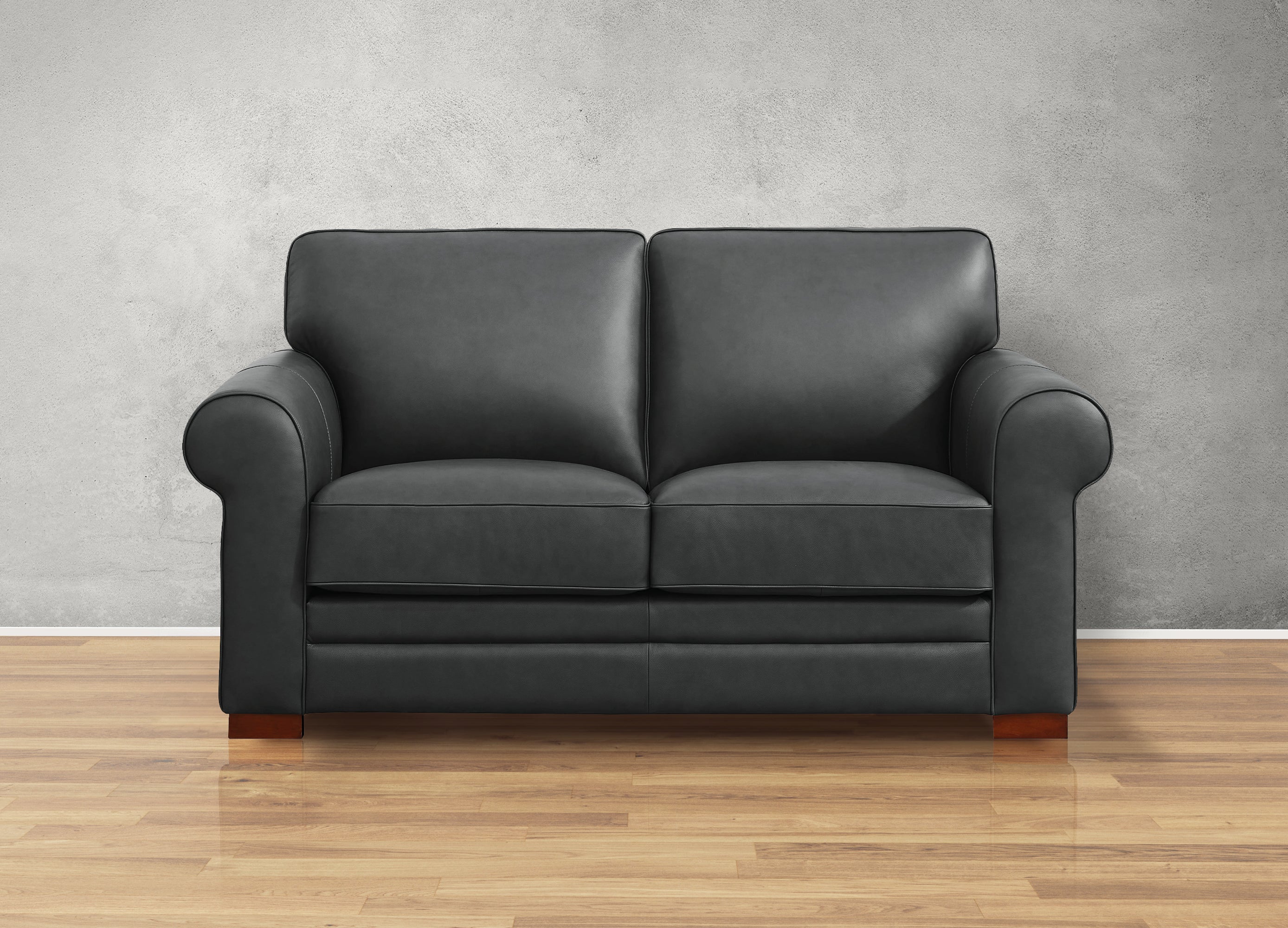 Black leather sofa on a wooden floor with a gray wall background
