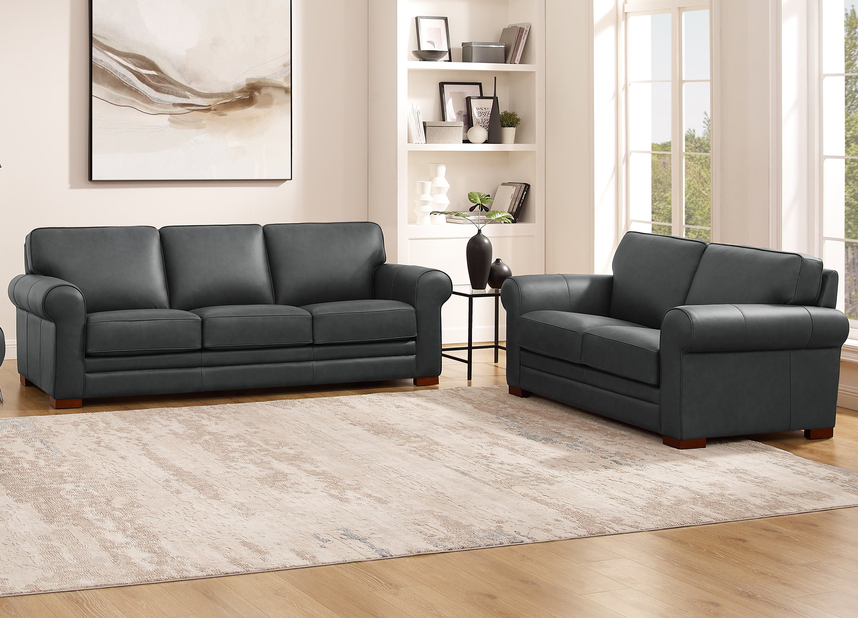 Brown leather sofa set in a living room with a rug and bookshelf.