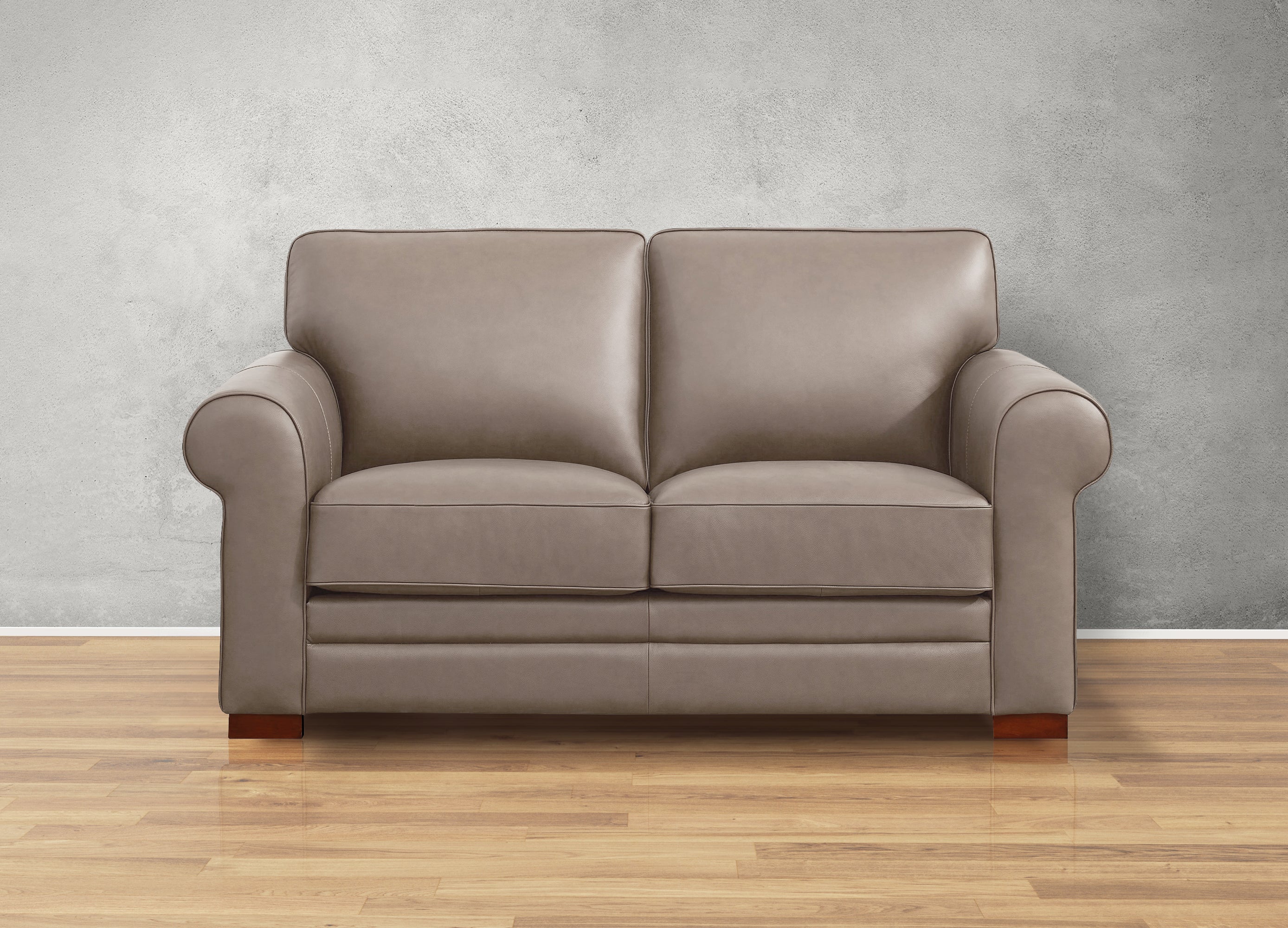 Beige leather sofa on a wooden floor with a gray wall background
