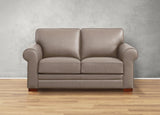 Beige leather sofa on a wooden floor with a gray wall background