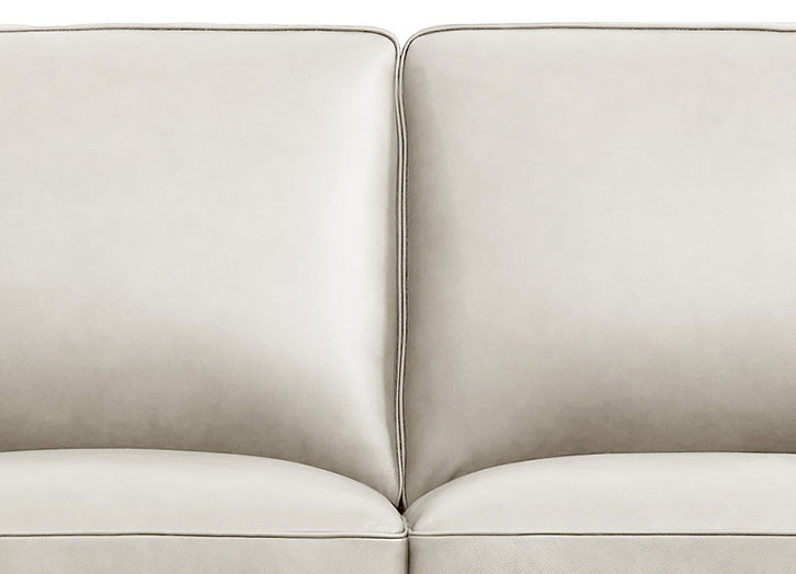 Close-up of a beige sofa with a plain background