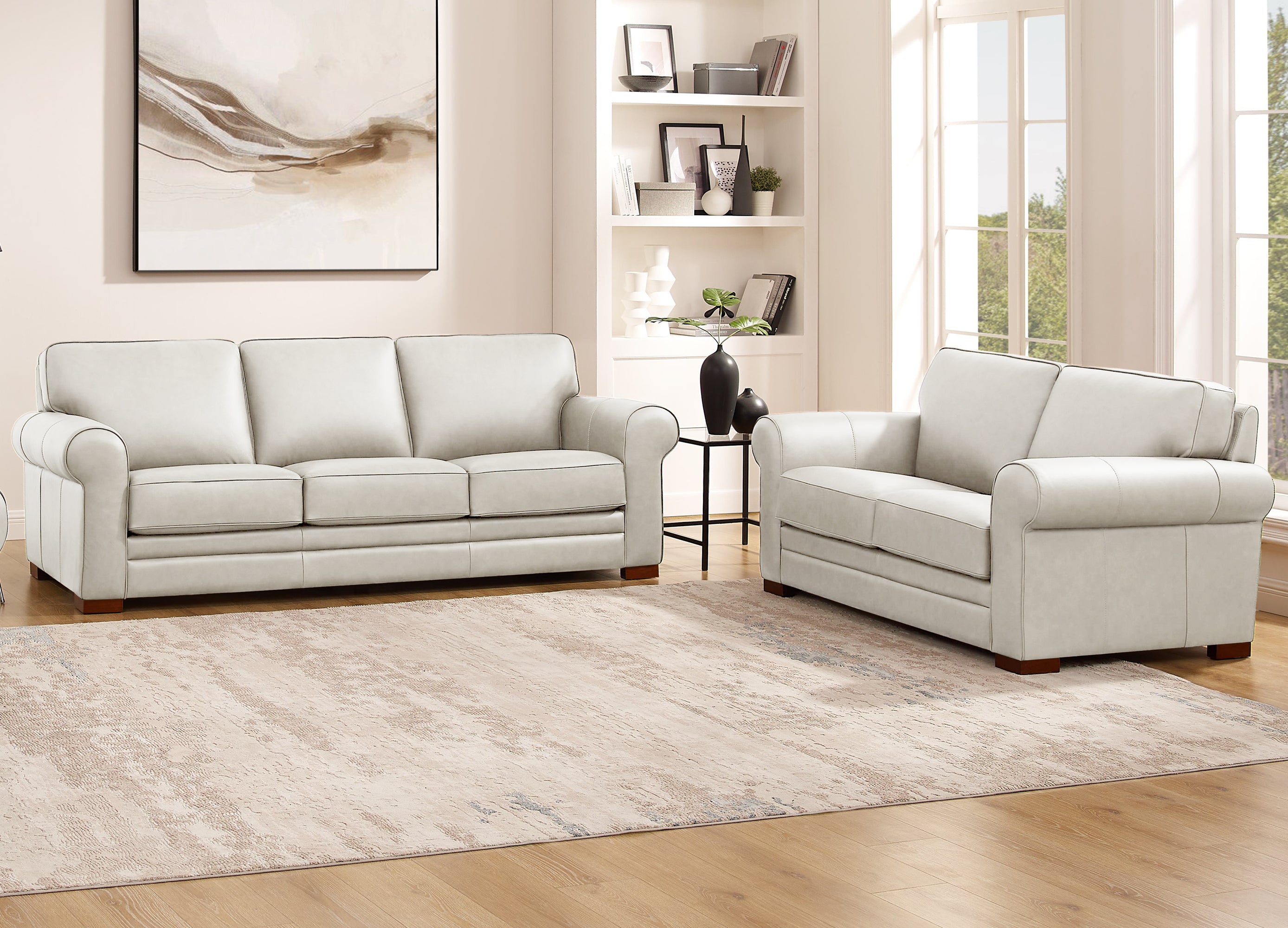 Light gray sofa set in a living room with a rug and wall art.