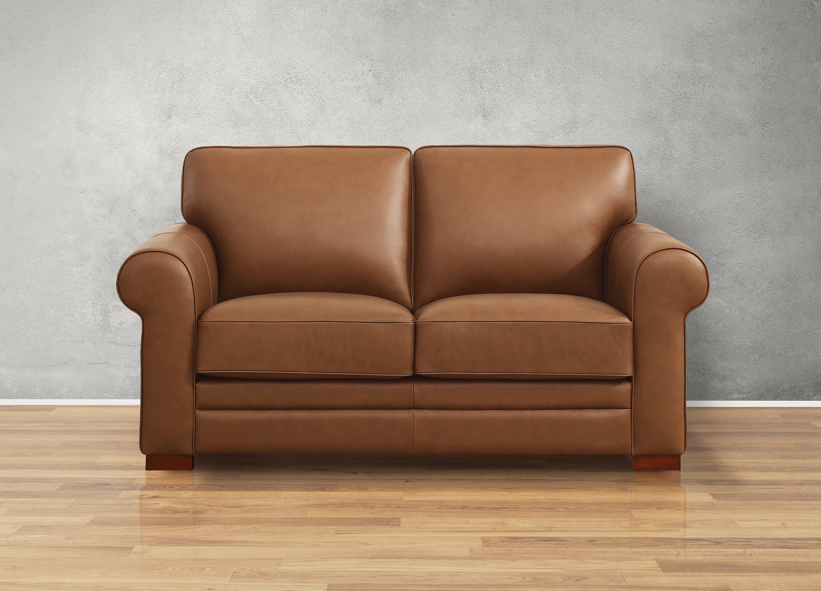 Brown leather sofa on a wooden floor with a gray wall background