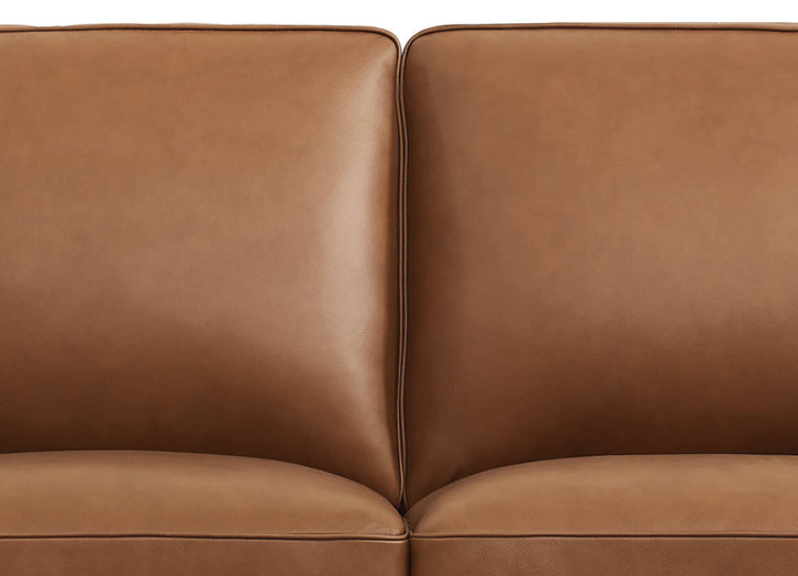 Close-up of a brown leather sofa with a plain background