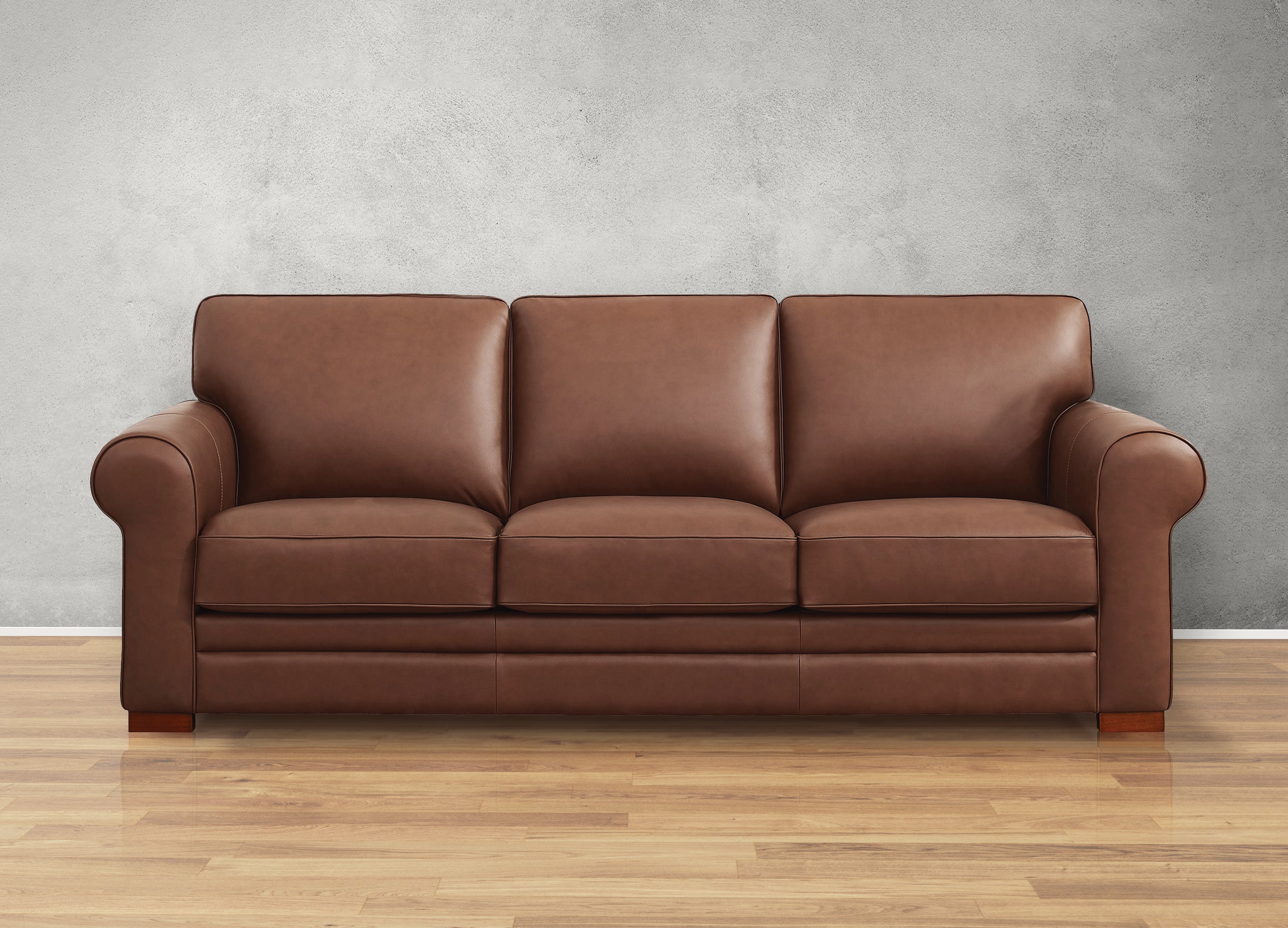 Brown leather sofa against a gray wall on a wooden floor