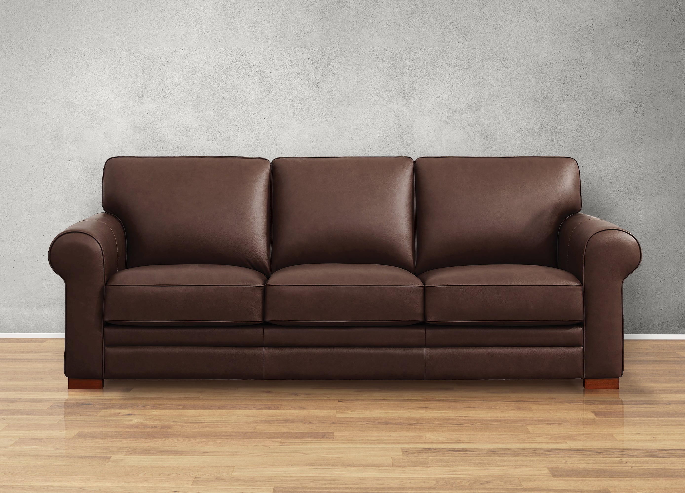 Brown leather sofa against a gray wall on a wooden floor